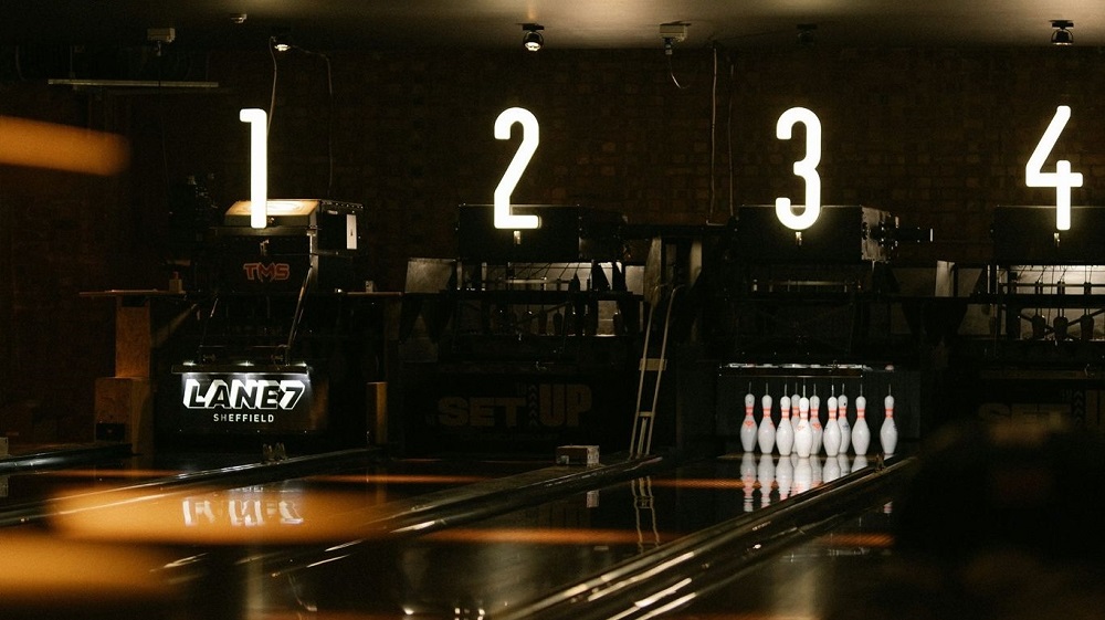 End of the bowling lanes at Lane7 Sheffield. Showing a set of string-pins and large glowing numbers 1 to 4 - the lane numbers.