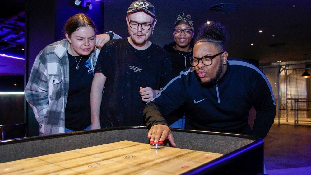 A group of people playing shuffleboard - similar to what will be available at Boom Battle Bar Ipswich