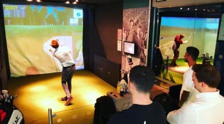 A group of guys playing in the golf simulator