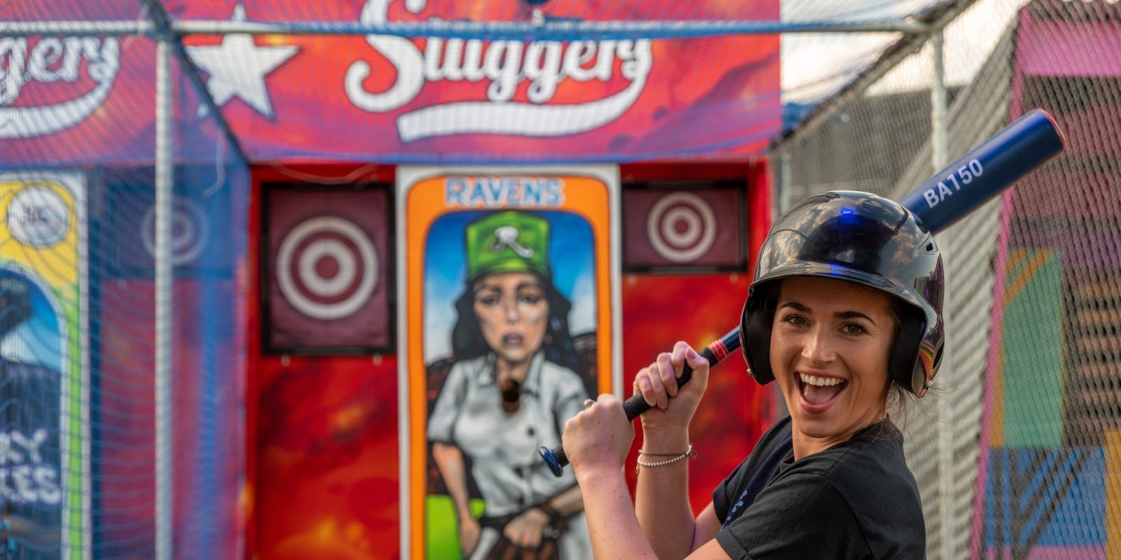 Girl with a baseball bat in a Sluggers batting cage